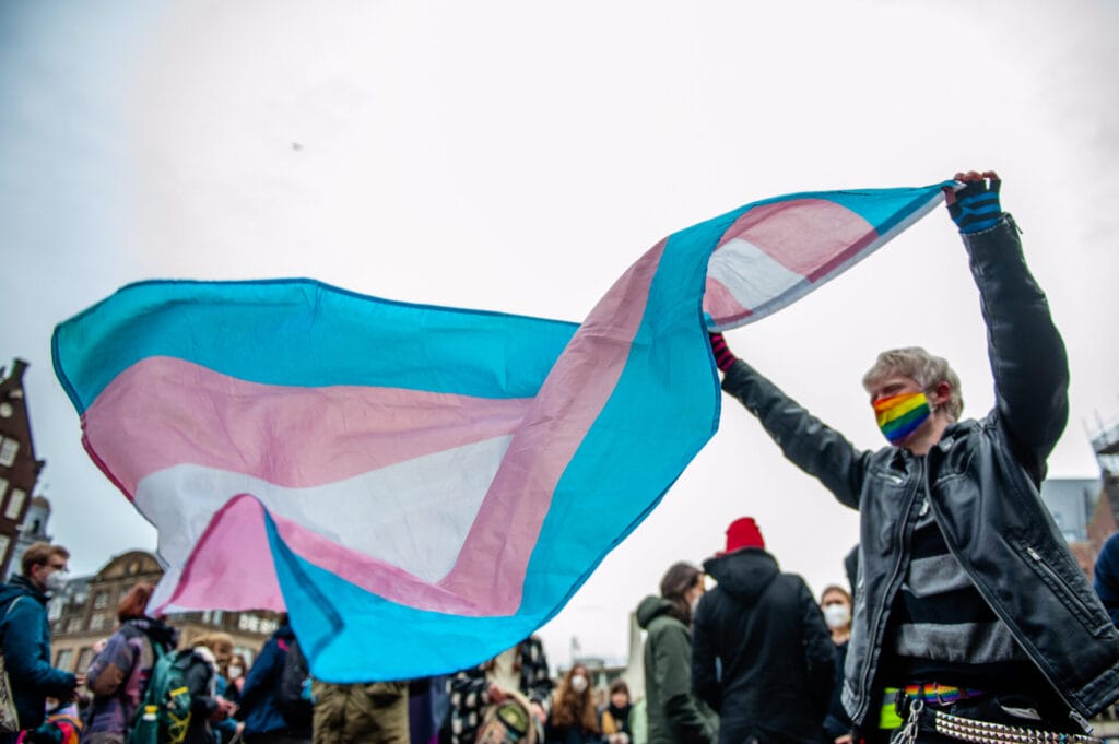 A protester is seen holding a transgender flag | GLAAD