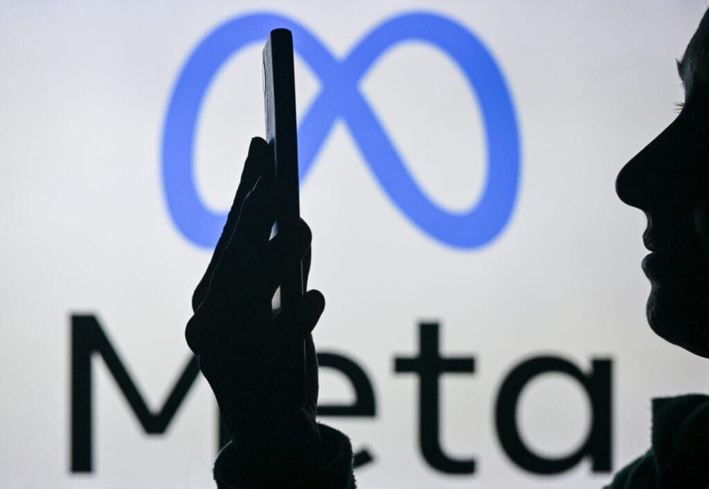 An image of a woman holding a cell phone in front of the Meta logo displayed on a computer screen, on April 29, 2024, in Edmonton, Canada.